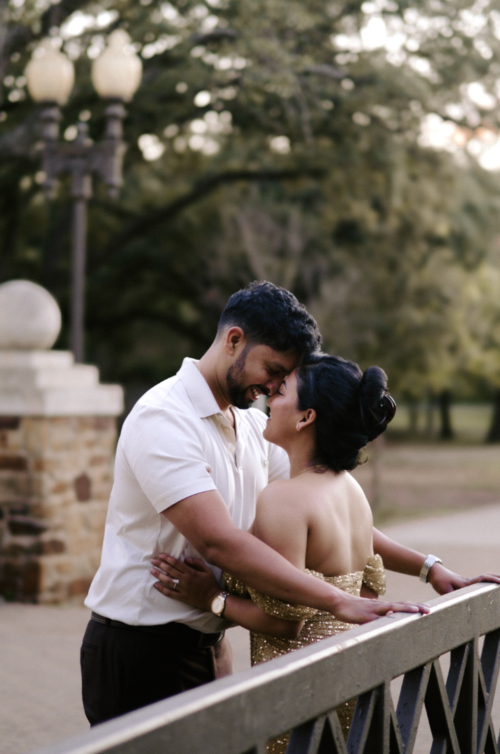 Couple embracing near a lamppost on a bridge at dusk
