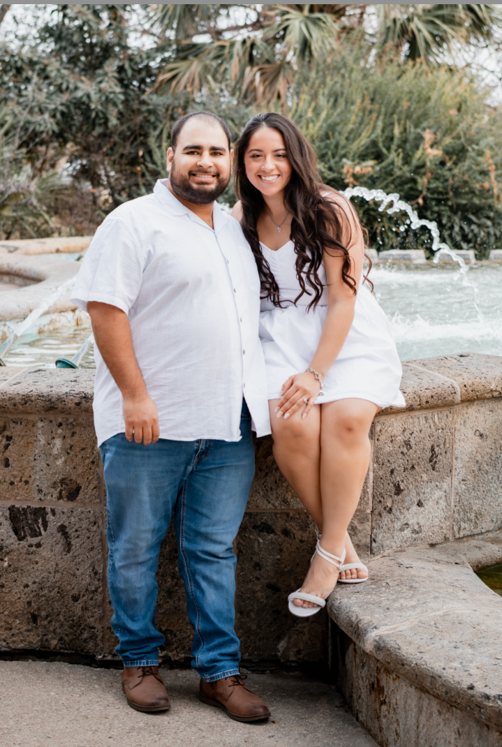 Couple seated at the edge of a fountain, smiling