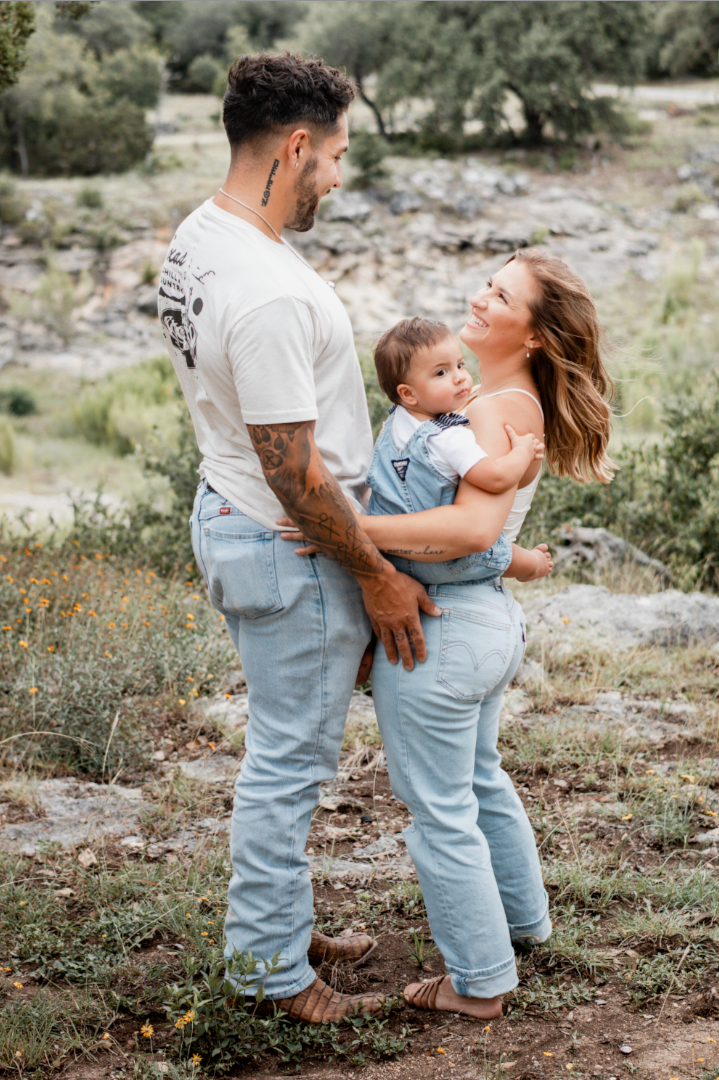 Family of three smiling together on a rocky hillside