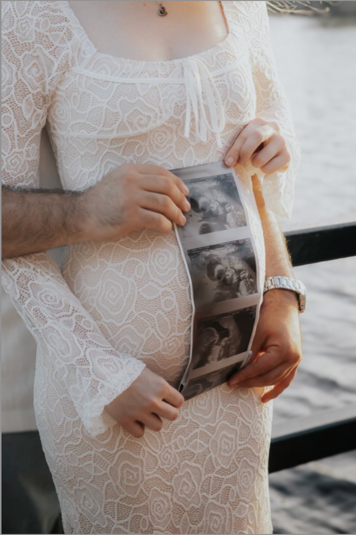 Expecting parents holding a black and white sonogram photo strip